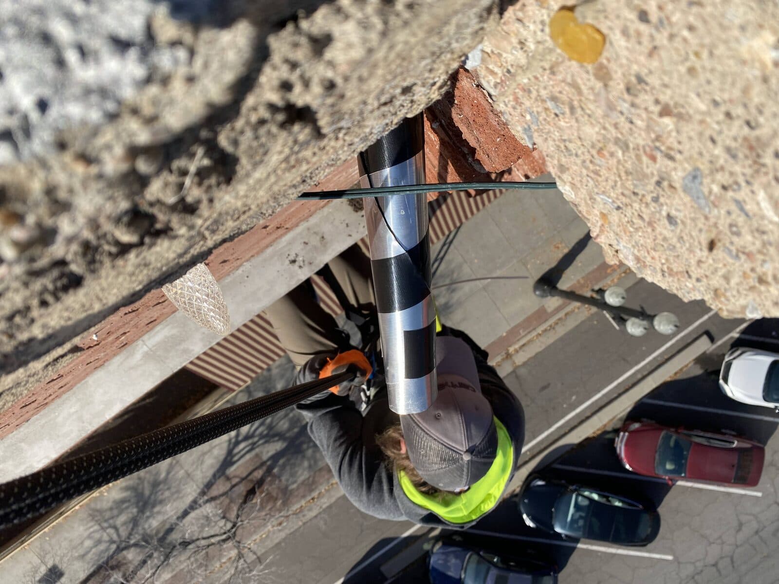 Rope-access technician installing a one-way exclusion tube on a multi-story building facade