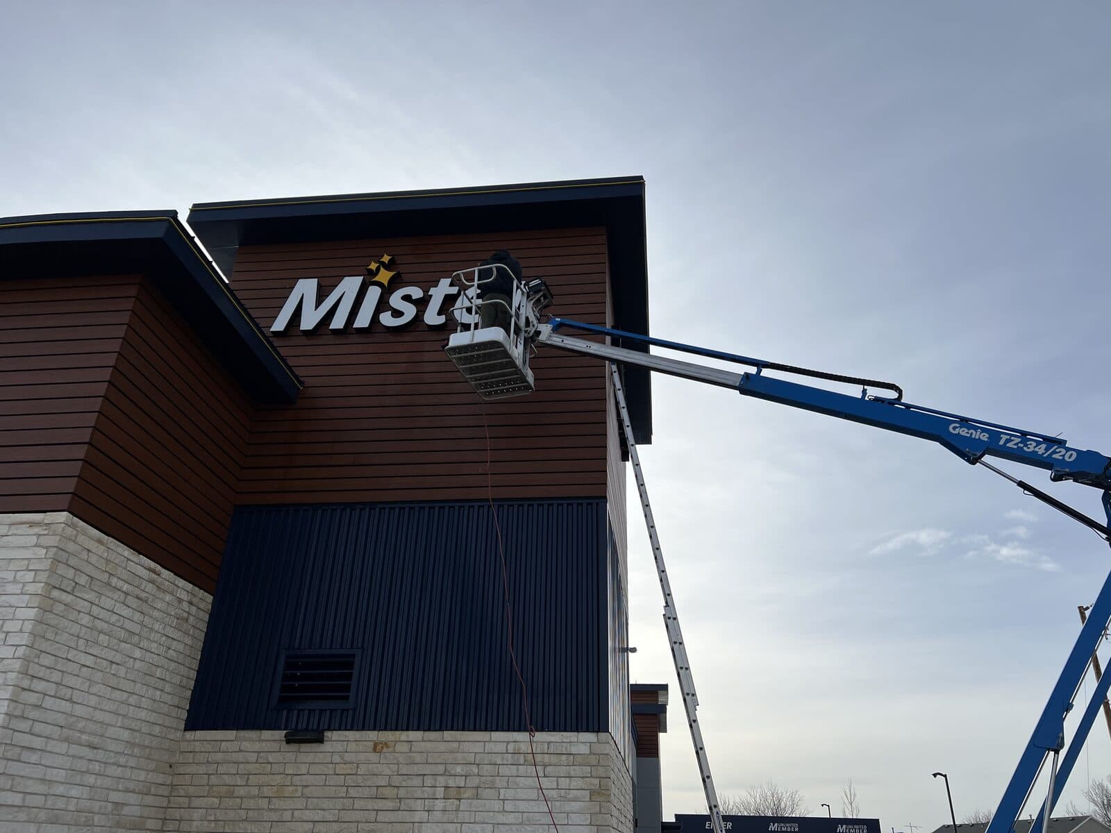 Blue articulated lift reaching a commercial building facade during elevated bat exclusion work